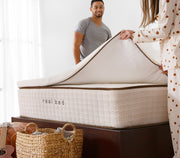 Man and woman putting on a Real Bed Topper. Image. 